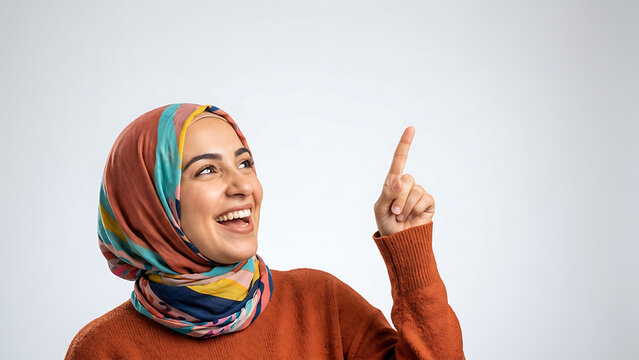 Happy Muslim woman in colorful hijab pointing at copy space