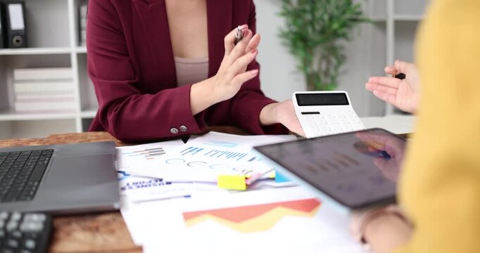 Businesswoman analyzing financial reports and accounting data, using a calculator and digital tablet for strategic planning and economic success in the modern office