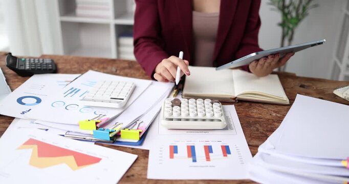 Businesswoman analyzing financial reports and accounting data, using a calculator and digital tablet for strategic planning and economic success in the modern office