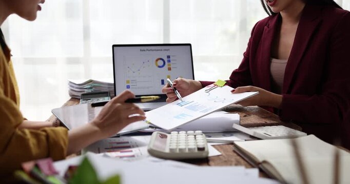 Businesswomen collaborating on financial data, analyzing reports and charts, planning investment strategies while working together in a professional office environment