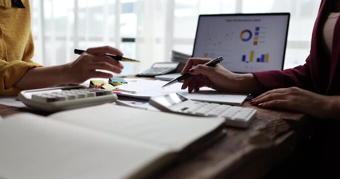 Businesswomen collaborating on financial data, analyzing reports and charts, planning investment strategies while working together in a professional office environment