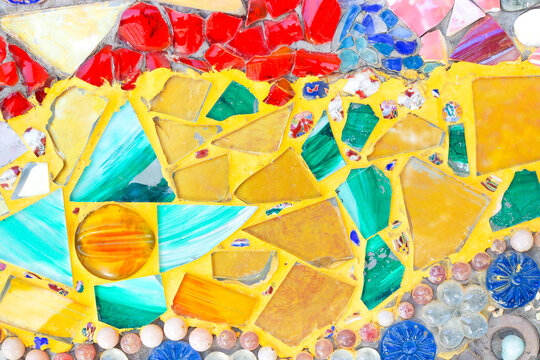 Colorful mosaic wall background made from broken tiles and stained glass pieces.