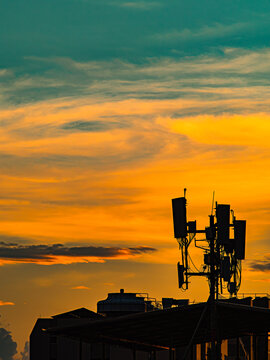 Silhouette of Cell Tower Antenna Array Against Dramatic Orange Sunset