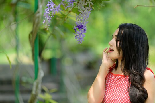 Woman in Red Dress Enjoying Nature in a Beautiful Flower Garden