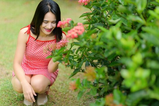 Woman in Red Dress Enjoying Nature in Tranquil Flower Garden