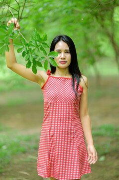 Woman in Red Dress Enjoying Nature in a Beautiful Flower Garden