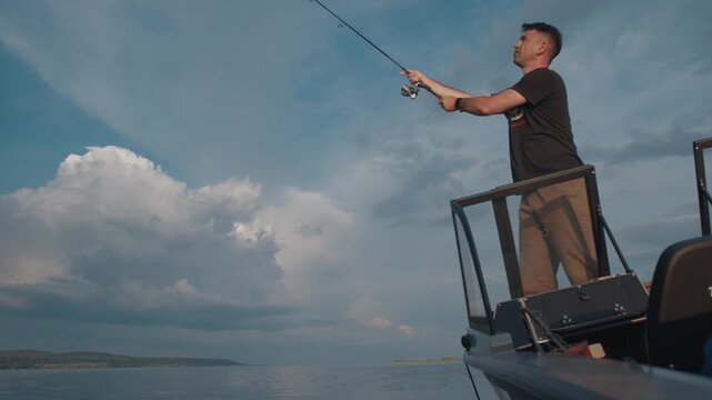Amateur angler fishing on the river from a boat at sunset