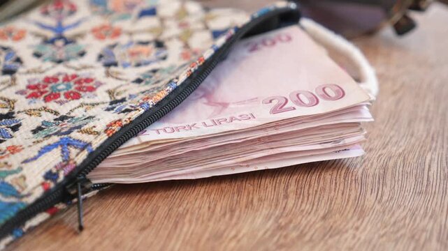 Turkish lira banknotes pile inside traditional ethnic patterned purse on wooden table clip.