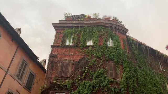 A shot of a beautiful Roman stone building completely clad in lush green ivy.