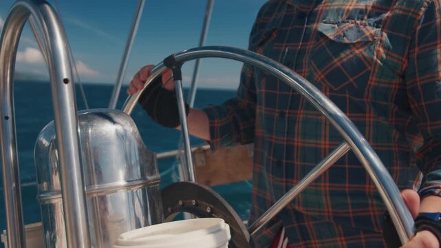 Young man sailor sailing alone the small sailing boat in the fresh sea during nice sunny day. Sailor enjoys the wind. Confident sailor steers the sail boat