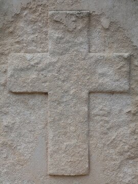 Close-up of a religious cross in relief on an old tombstone. White, weathered stone texture. Background. Theme: All Saints' Day.