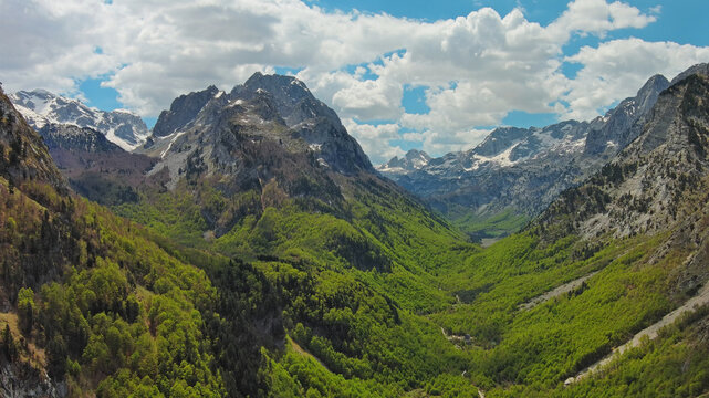 Rocky snow mountains and green valley aerial