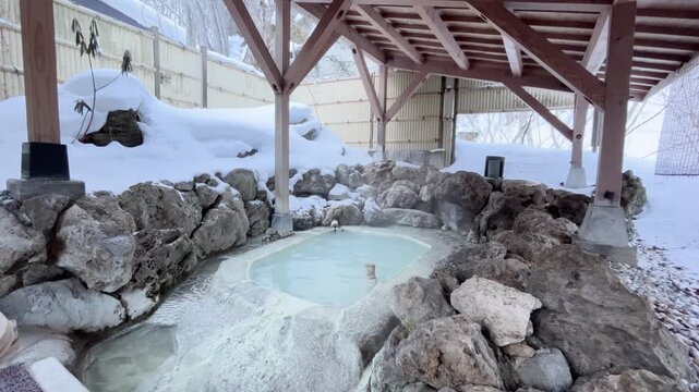 長野県 白骨温泉 木造の東屋と雪積もる岩に囲まれた乳白色の雪見露天風呂
