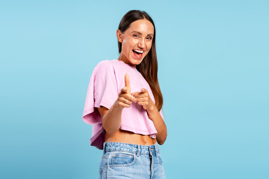 Happy young woman pointing fingers smiling at camera