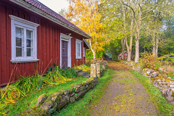 Red wooden cottage along dirt road at rural Swedish countryside © Lars Johansson