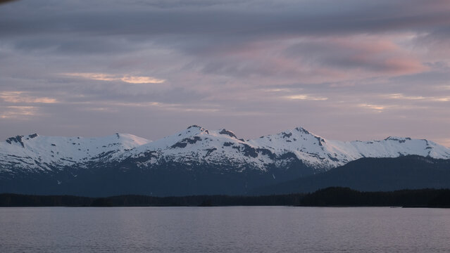 Breathtaking Alaska mountain glacier range view seen from outdoor deck of cruise ship liner sailing the Inside Passage transit with spectacular landscape scenery during sunset