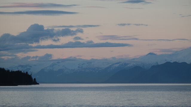 Breathtaking Alaska mountain glacier range view seen from outdoor deck of cruise ship liner sailing the Inside Passage transit with spectacular landscape scenery during sunset