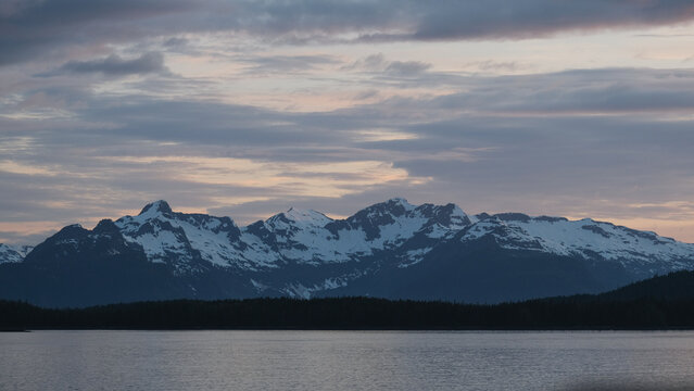 Breathtaking Alaska mountain glacier range view seen from outdoor deck of cruise ship liner sailing the Inside Passage transit with spectacular landscape scenery during sunset