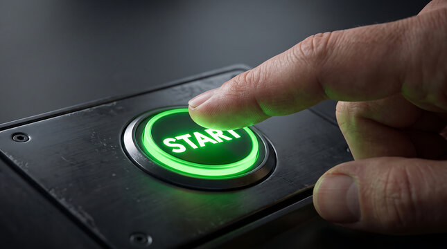 A close up view of a human finger pressing a glowing green start button on a machine