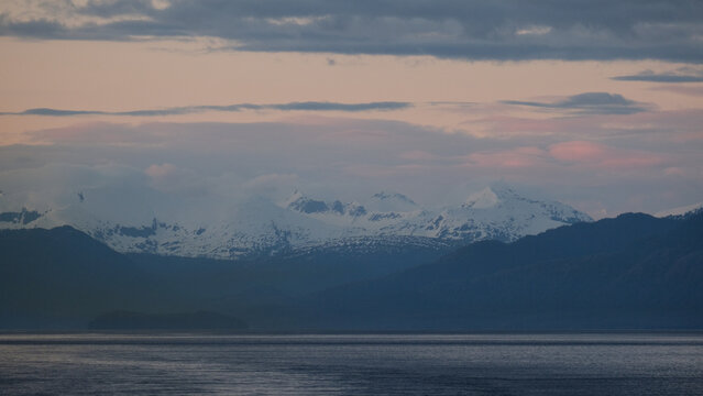 Breathtaking Alaska mountain glacier range view seen from outdoor deck of cruise ship liner sailing the Inside Passage transit with spectacular landscape scenery during sunset