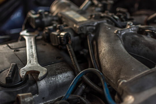 Closeup of used car engine metal wrench resting mechanical components highlighting automotive maintenance repair inspection workshop service