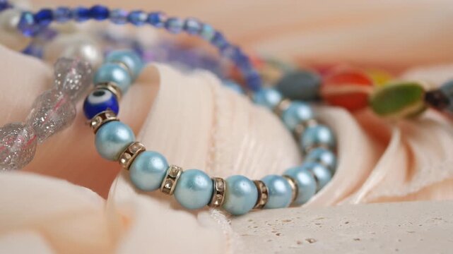 Blue pearl bracelet and colorful beaded jewelry on soft fabric background cinematic video.