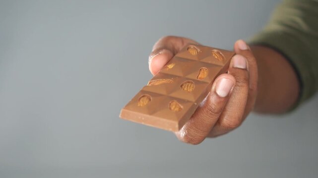 Hand holding almond chocolate bar offering sweet treat for indulgence snack delicious.