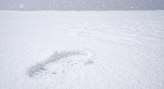 single boot footprint in fresh white snow during winter snowfall