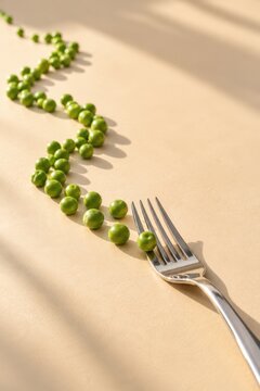 Green peas arranged in a winding path leading toward a stainless steel fork on a warm beige surface with sunlight and shadows. Concept of healthy eating, nutrition and fresh food