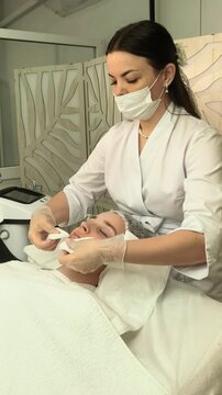 Beautician cleanses a teenage girl's face during a professional skincare treatment in a beauty salon, gentle facial care, hygiene and healthy complexion.