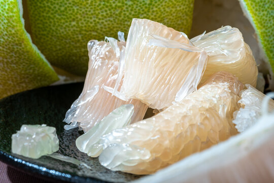 Detailed close-up of translucent juicy pomelo pulp segments on a plate.