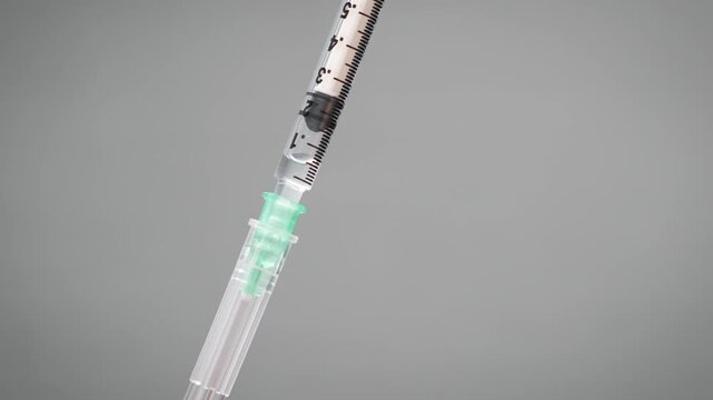 Close up of a plunger slowly pulled back drawing air bubbles into the oily liquid inside a syringe [TRT Concept]