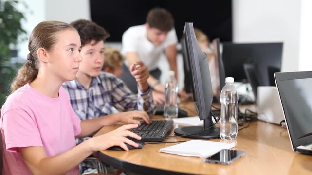 Curious underage girl and boy engaged in IT training during computer courses for children 