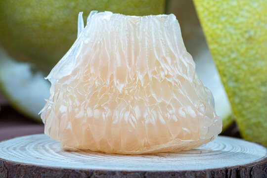 Front view of a thick juicy pomelo segment placed on a plate.
