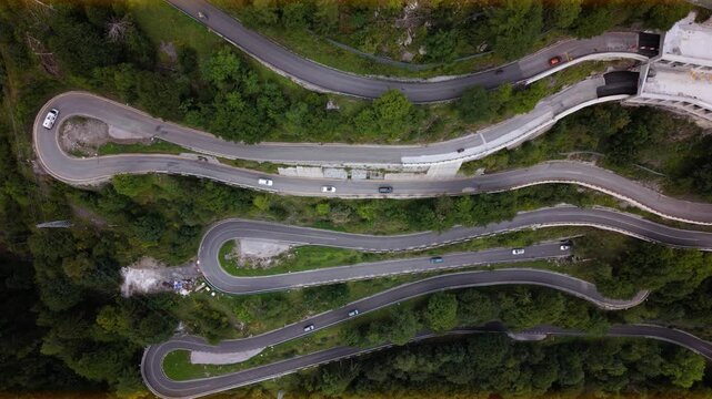 Cars driving sharp serpentine bends on mountain road. Carnic Alps, Plocken Pass top down aerial view