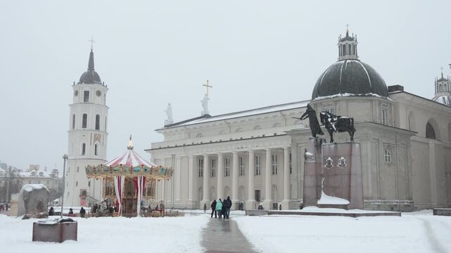  City landmark, religious building - City Cathedral church on Cathedral Square during New Year holidays, carousel and monument to Prince Gediminas. 