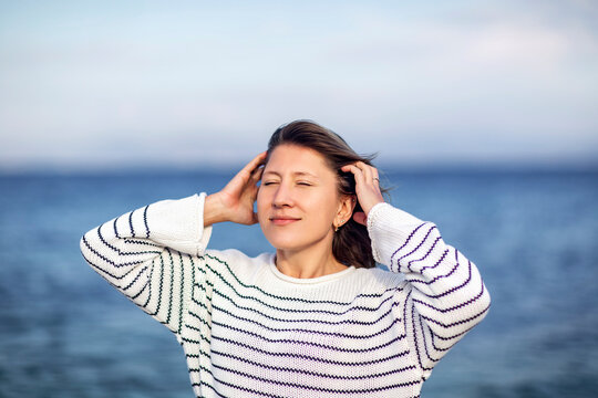 Serene woman with eyes closed enjoying the sea breeze