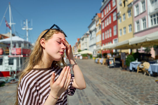 Young woman shields her face from bright summer sun