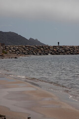 Fototapeta premium Person standing on rocky breakwater viewing calm sea