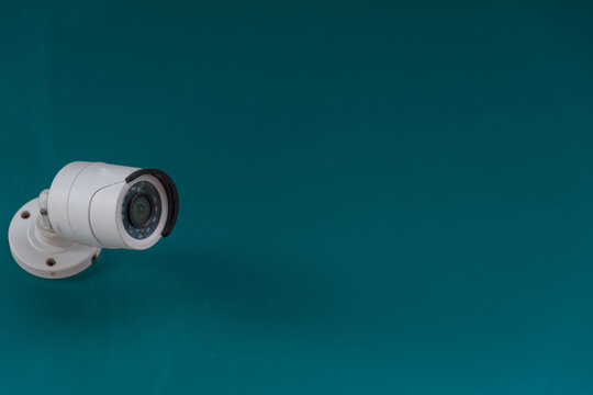 Security surveillance camera mounted teal wall large copy space representing monitoring protection safety observation property security