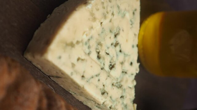 A close up view of a triangle slice of blue cheese next to a jar of honey.