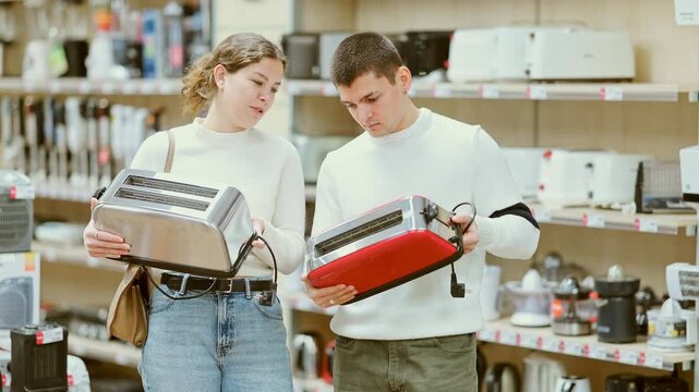 Couple choose a toaster for a kitchen. Guy helps young woman with the purchase of an electric toaster for bread in the household appliances. Two customers in the kitchen appliance department . High
