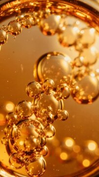 Close up of golden bubbles with warm glowing light and reflective surface in liquid environment
