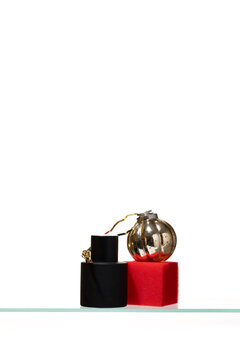Minimalist beauty concept featuring a matte black cylinder and a vibrant red textured cube topped with a vintage gold glass ornament, reflecting a modern and artistic approach to cosmetics.