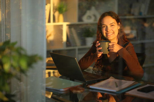 Happy telecommuter taking a break drinking coffee working at home