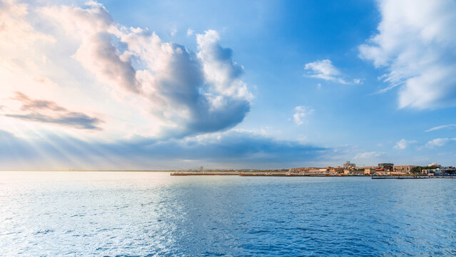 Scenic view over calm blue sea with dramatic cloudy sky and sunbeams