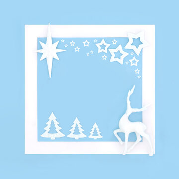 Christmas trees, reindeer, star bauble decorations border background, white frame on pastel blue. Xmas North Pole design for greeting card.