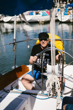 Man at the helm of his sailboat on a sunny day