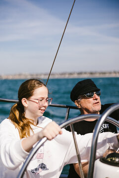 Man teaching a teenage girl to steer a sailboat