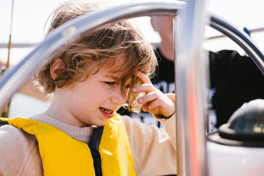 Young boy wearing a life vest steering a boat